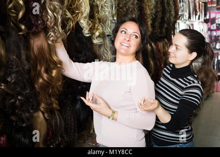 Due donna positivo ai clienti che acquistano prodotti di estensione dei capelli in salone Foto Stock