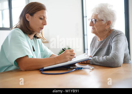 L'infermiera dando la prescrizione di donna anziana Foto Stock