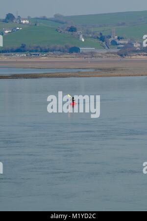 Lone Kayaker Paddling in rosso di un kayak sul fiume Taw in un paesaggio di rullatura di Devon Farmland, passato il North Devon Villaggio di Pescatori di Appledore. Regno Unito. Foto Stock