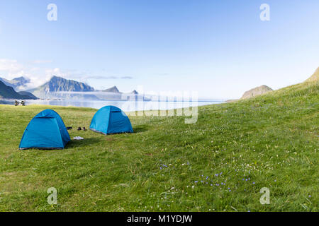 Due le tende nel prato verde di fronte al mare. Haukland Beach, Isole Lofoten in Norvegia. Foto Stock