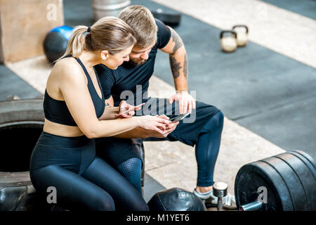 Giovane usando il telefono in palestra Foto Stock