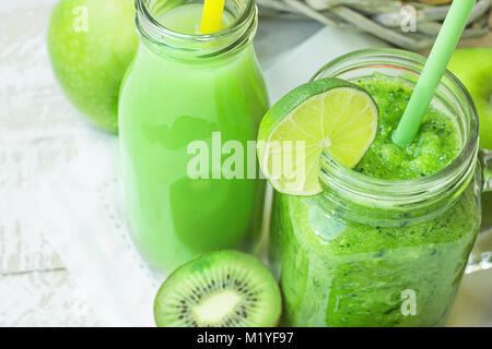 Vetro Mason Jar e bottiglia con verdura verde e il frullato di frutta e succhi di frutta con la paglia. Cestello stagionali con prodotti biologici in background. La molla su Foto Stock