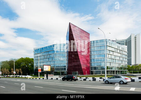 Minsk, Bielorussia - 18 Maggio 2017: un edificio moderno nella città di Minsk con una strada e automobili in primo piano Foto Stock