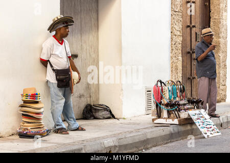 Cartagena, Colombia - Gennaio 23th, 2018: un cappello venditore ambulante e collane e negozio di souvenir fornitore sta in piedi in una vecchia strada di Cartagena. Foto Stock