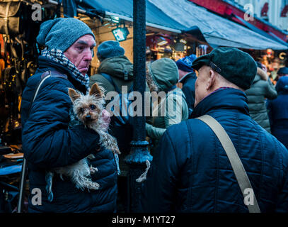 Due uomini faccia a faccia, una holding cane, Portobello, Londra, Inghilterra Foto Stock