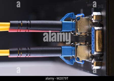 Dispositivi di rete tecnologia, cavo in fibra ottica e interruttore, close-up su sfondo nero Foto Stock