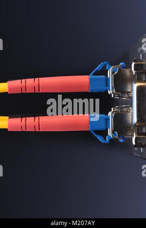 Dispositivi di rete tecnologia, cavo in fibra ottica e interruttore, close-up su sfondo nero Foto Stock