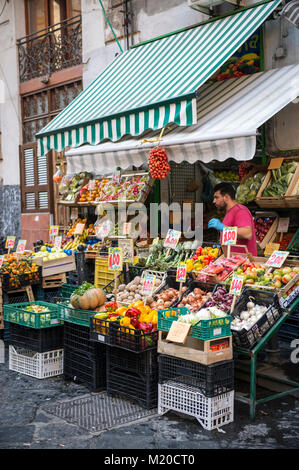 Napoli, Italia - 16 ottobre 2017: un fornitore tende la sua merce a un mercato di frutta e verdura stallo nella storica vecchia parte della città. Foto Stock