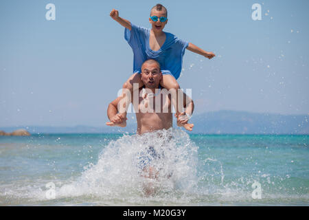 Gli spruzzi di figlio Padre spalle mare divertente Foto Stock