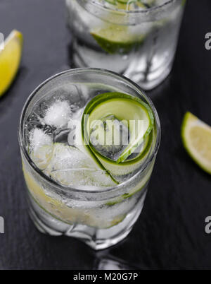 Il gin tonic con il cetriolo, calce e il ghiaccio in vetro Foto Stock