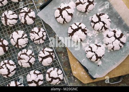 Cioccolato artigianale Crinkle Cookies su un vassoio da forno e raffreddamento per rack su sfondo di ardesia Foto Stock