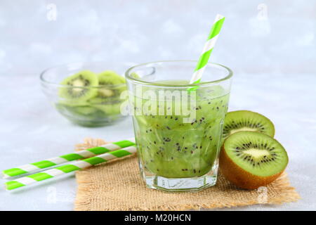 Fette di kiwi frullato e fette in un vetro in una tabella di colore grigio. Cibo sano Foto Stock