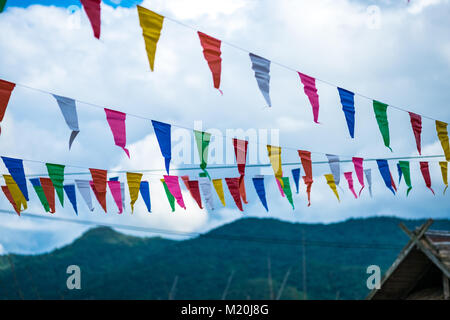 Colorato piccolo bandiere fatte di carta appeso a una fune con cielo blu di sfondo, il fuoco selettivo. Foto Stock