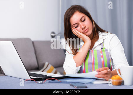 Giovane donna navigando attraverso utili suggerimenti per la cottura in Internet Foto Stock