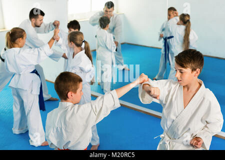 Diligente adolescenti seri praticanti di karate nuovo si muove in coppie in classe Foto Stock
