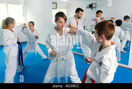 Positivo gravi adolescenti praticanti di karate nuovo si muove in coppie in classe Foto Stock