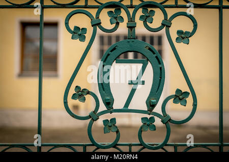 Numero di casa sette su un verde cancello di ferro, circondato da un ferro di cavallo Foto Stock