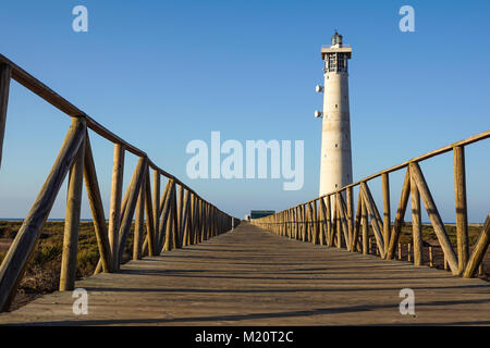 Passerella in legno passaggio pedonale alla spiaggia nei pressi di Morro Jable faro nella calda luce del tramonto, isola di Fuerteventura, Spagna Foto Stock