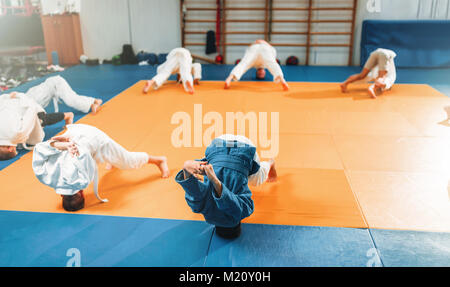 Bambini judo, kids in kimono pratica delle arti marziali di hall. Bambini e bambine in uniforme sulla formazione sportiva Foto Stock