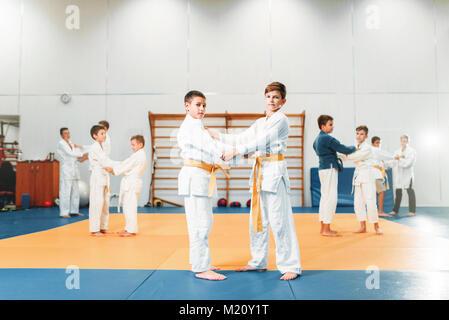 Kid judo, corsi di formazione per bambini arte marziale nella hall. Ragazzi piccoli in uniforme, giovani combattenti Foto Stock