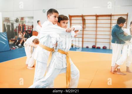 Kid judo, corsi di formazione per bambini arte marziale nella hall. Ragazzi piccoli in uniforme, giovani combattenti Foto Stock