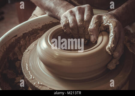 Uomo anziano rendendo pot con ruota di ceramiche in studio. Close-up. Foto Stock