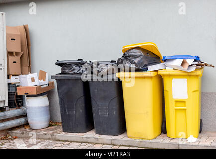 Traboccante di rifiuti di plastica lattine con il nero di sacchi, scatole di cartone e un contenitore con un liquido Foto Stock