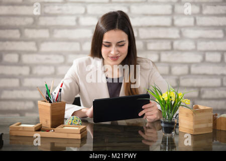 Sorridente giovane imprenditrice utilizzando digitale compressa in Office Foto Stock