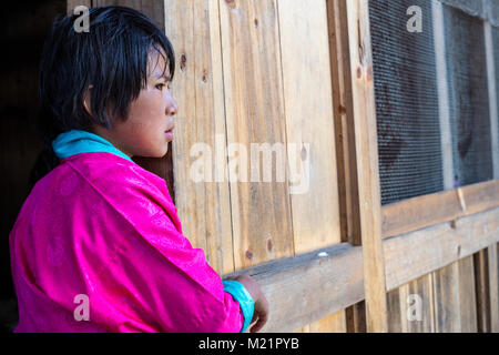 Prakhar Lhakhang, Bumthang, Bhutan. Giovane ragazza bhutanesi in piedi in cucina porta. Foto Stock