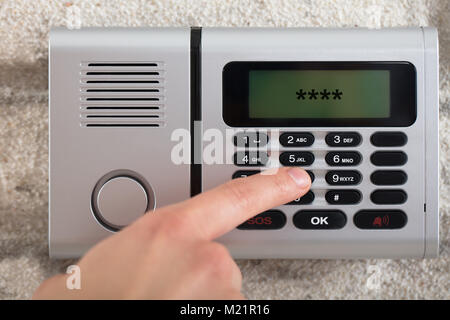 Close-up di mano di una persona sulla sicurezza tastiera allarme Inserimento del codice di protezione Foto Stock