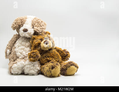 2 marrone di peluche orsacchiotto appoggiato su ogni altra isolata su uno sfondo a tinta unita Foto Stock