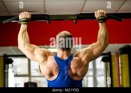 Muscoloso bodybuilder con corpo forte facendo chin-up, esercizi di formazione presso la palestra Foto Stock