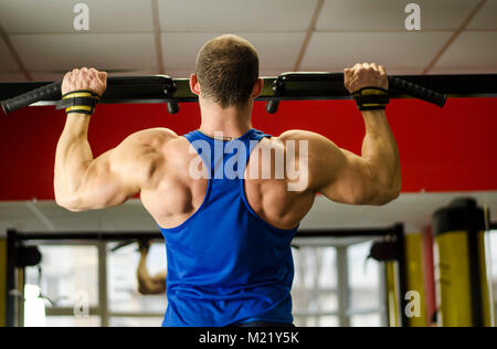 Professional bodybuilder con ideale corpo muscoloso facendo pull-up nella palestra Foto Stock