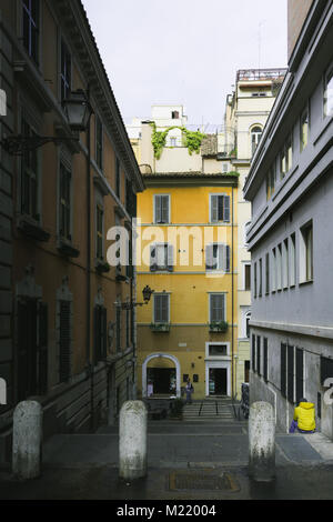 Luce che mostra l'uomo con la giacca gialla sitted tra gli edifici in una pubblica strada romana Foto Stock