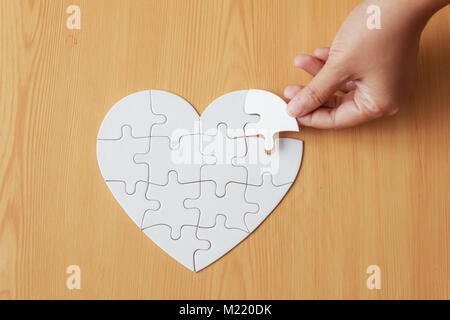 Immagine ravvicinata mano di donna giocando puzzle sul tavolo di legno Foto Stock