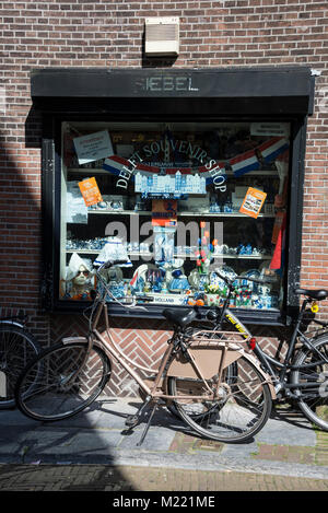 Un paio di biciclette parcheggiate nella parte anteriore di un turista souvenir shop finestra con nessuna vera Delftware in Delft, Olanda. La vera e propria prodotti abile carr Foto Stock
