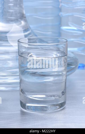 Il vetro e la caraffa con acqua sul tavolo in metallo Foto Stock