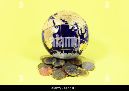 Blu e Oro globe seduto sulla cima di un palo di una miscela delle monete metalliche da parte degli Stati Uniti in Europa e Gran Bretagna Foto Stock