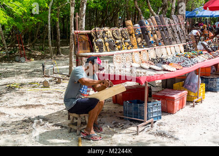 Chichén-Itzá, Yucatan, Messico, uomo messicano che crea una tradizionale maschera maya di legno presso lo stand souvenir, solo editoriale. Foto Stock