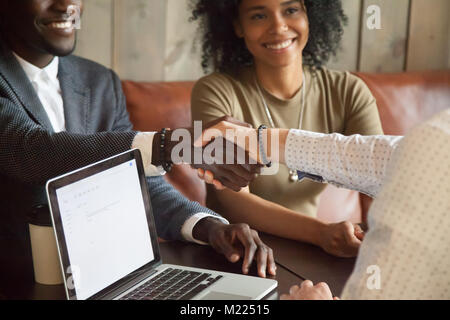 Felice americano africano giovane rendendo trattativa caucasici di handshaking Foto Stock
