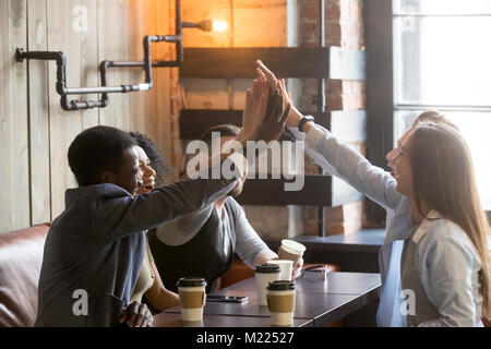 Diversi amici partecipare le mani insieme dando ad alta cinque presso il cafe mee Foto Stock