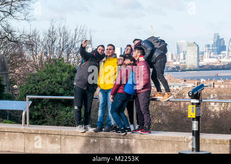 Un gruppo di amici prendendo un selfie a Greenwich davanti la vista sul fiume Tamigi a Isle of Dogs, Foto Stock