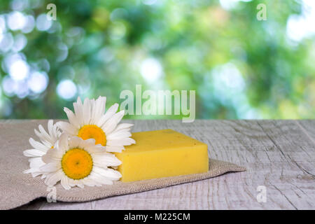 Naturale saponi fatti a mano e i fiori di camomilla su un sfondo di legno Foto Stock