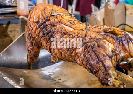 Uno spiedo di maiale arrosto su un mercato in stallo nel mercato di Borough, Londra Foto Stock