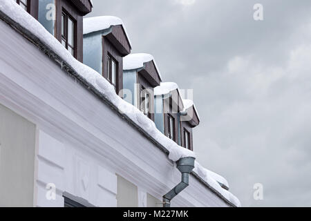 Il tetto coperto di neve spessa e ghiaccioli. city building vista in inverno. Foto Stock