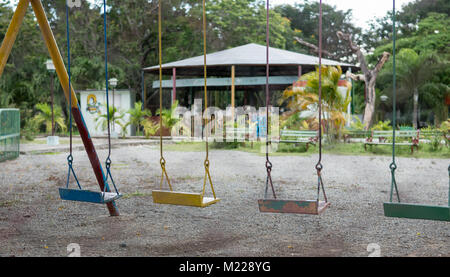 Las Tunas, Cuba - 4 Settembre 2017: Swingset con quattro diverse altalene colorate in un parco giochi vuoto nella città. Foto Stock