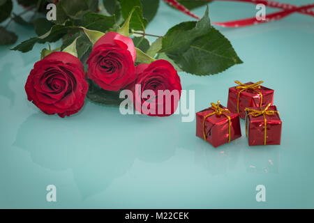 Occasionali di bellissime rose rosse con piccole scatole di doni sullo sfondo Foto Stock