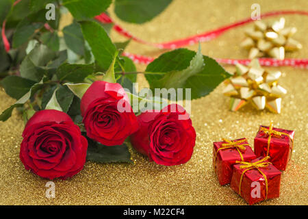 Occasionali di bellissime rose rosse con piccole scatole di doni sullo sfondo Foto Stock