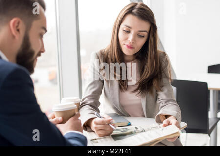 Ritratto di due persone di affari a pausa caffè nella caffetteria, concentrarsi sul giovane e bella donna quotidiano di lettura Foto Stock