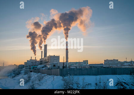 Un impianto per garantire il riscaldamento per il popolo di Yakutsk in Siberia rilascia fumo nell'aria come tramonto. Yakutsk è un importante porto sul fiume Lena. Foto Stock